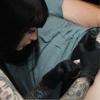 a woman getting tattooed on her thigh
