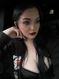 a woman sitting in a car with tattoos on her face